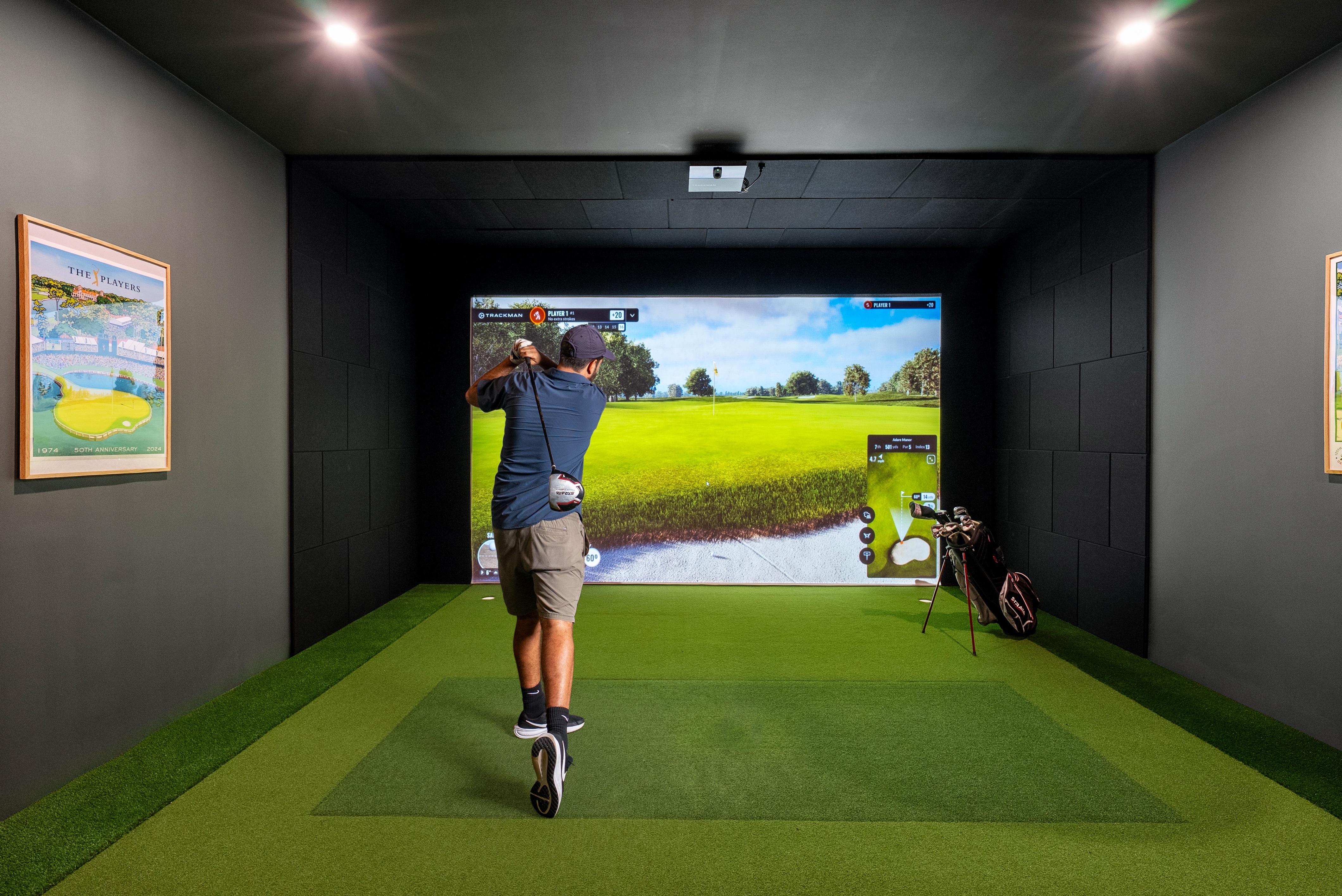 A man is playing a golf game on a screen in a room.